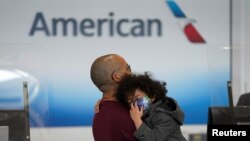 Dua orang pengunjung Nasional Ronald Reagan Washington di Arlington, Virginia, terlihat masih mengenakan masker setelah adanya pengumuman bahwa pemerintahan Biden tidak lagi memberlakukan mandat pemakaian masker pada transportasi umum, 19 April 2022. (REUTERS/Kevin Lamarque)