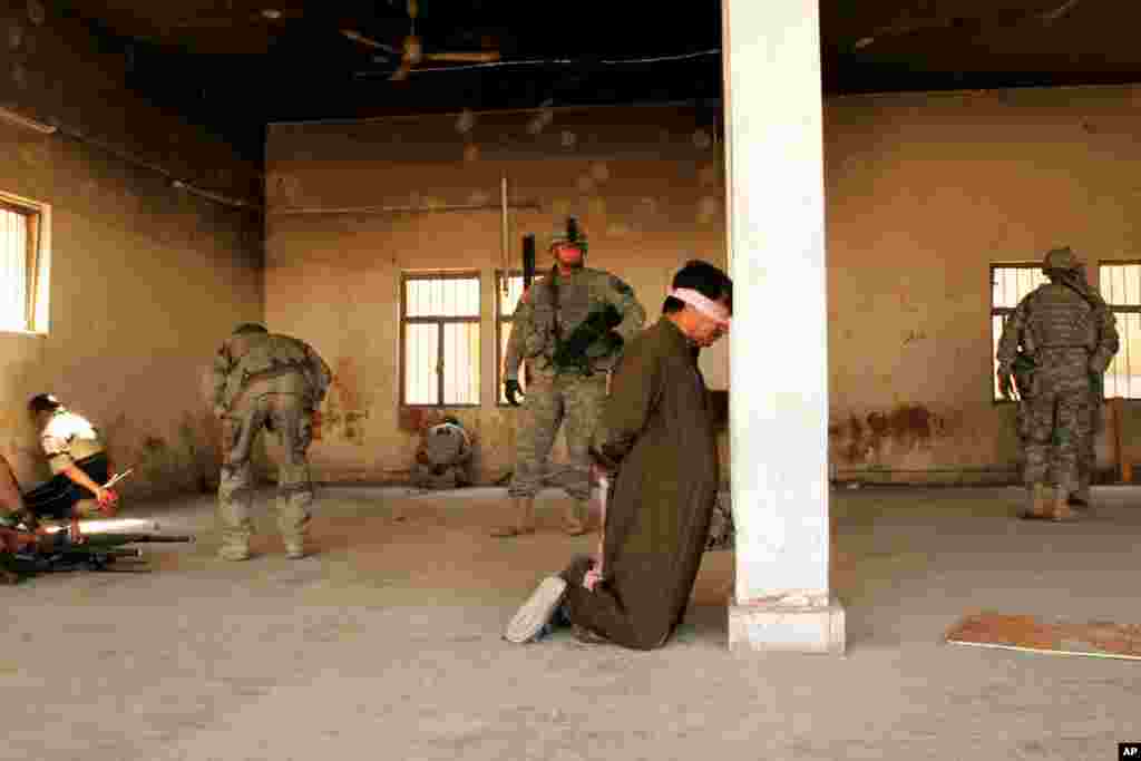 一名美国士兵于2007年3月29日在伊拉克巴古拜中心地区的一次枪战之后,看守着他逮捕的一个人。