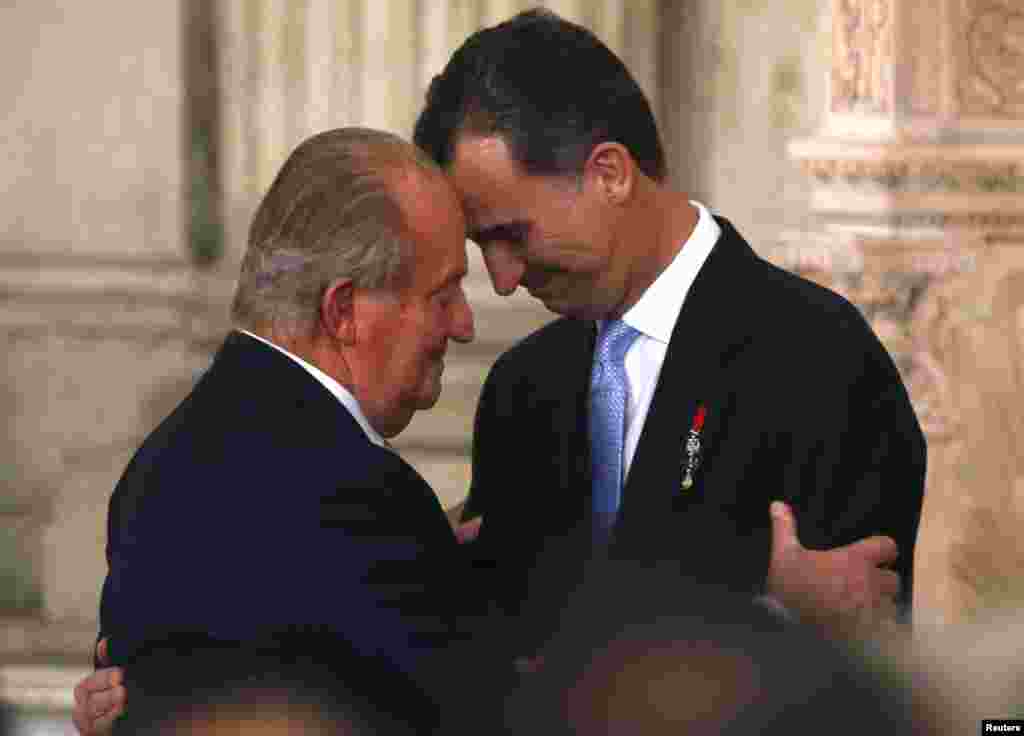Raja Spanyol Juan Carlos (kiri) dan putera mahkota Felipe berpelukan dalam upacara turun tahta di Kerajaan Spanyol di Madrid.