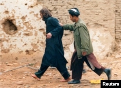 FILE - U.S.-born John Walker Lindh, left, is led away by a Northern Alliance soldier after he was captured among al-Qaida and Taliban prisoners following an uprising at the Fort Qali-i-Janghi prison near Mazar-i-Sharif, Dec. 1, 2001.