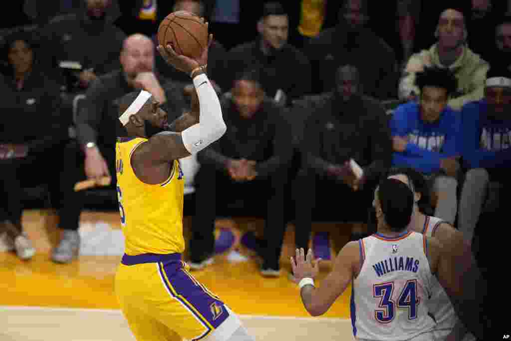 Los Angeles Lakers forward LeBron James, left, scores to pass Kareem Abdul-Jabbar to become the NBA's all-time leading scorer as Oklahoma City Thunder guard Josh Giddey, right, and forward Kenrich Williams defend during the second half of an NBA basketball game, Feb. 7, 2023, in Los Angeles.