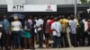 FILE - People queue to withdraw new naira notes from an Automated Teller Machine (ATM) on bank premises in Lagos, Feb. 1, 2023.