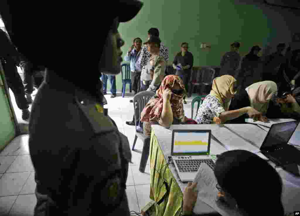 Seorang petugas keamanan perempuan berjaga-jaga sementara para pekerja seks yang setuju meninggalkan kompleks lokalisasi antre mendaftar untuk menerima uang kompensasi dari pemerintah kota, di sebuah kantor militer lokal di Surabaya. (AP/Dita Alangkara)