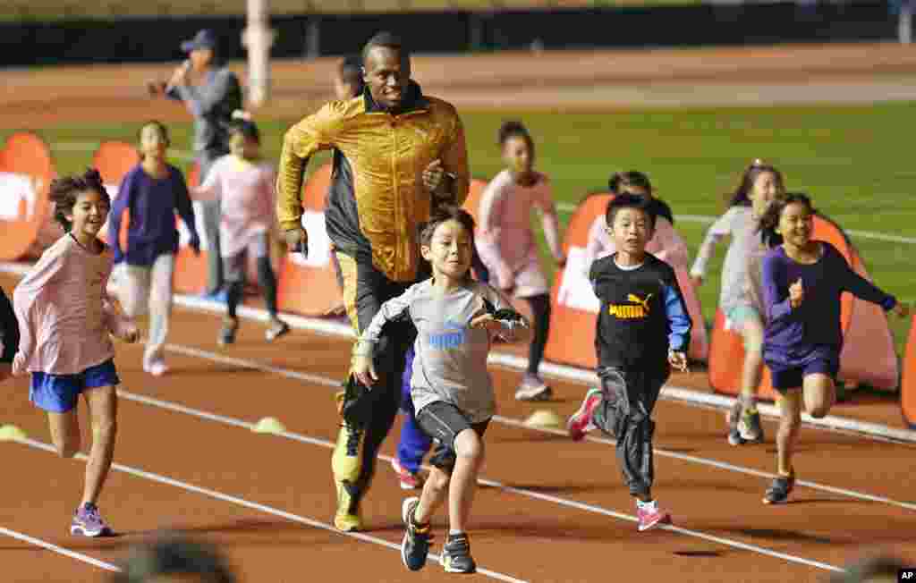 Peraih medali emas olimpiade Usain Bolt dari Jamaika "berkompetisi" dengan anak-anak dalam acara "Klinik Atletik" di Stadion Nasional di Tokyo, Jepang.