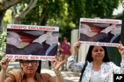 FILE - Members of the movement Laicos de Osorno hold images of the Rev. Fernando Karadima, and his protege Juan Barros, bishop of Osorno, with a message that reads in Spanish: "A bishop who covers up cannot be a priest," during a demonstration.