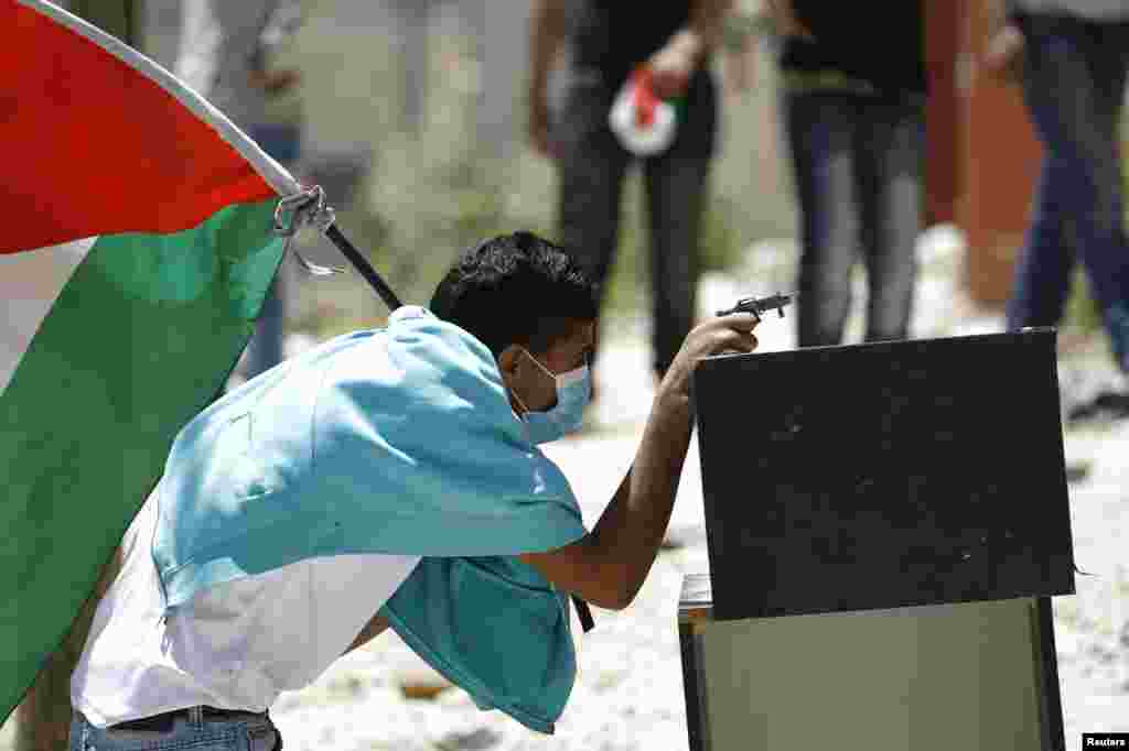 Seorang demonstran Palestina menggunakan pistol mainan saat bentrok dengan pasukan Israel di Ramallah, Tepi Barat.