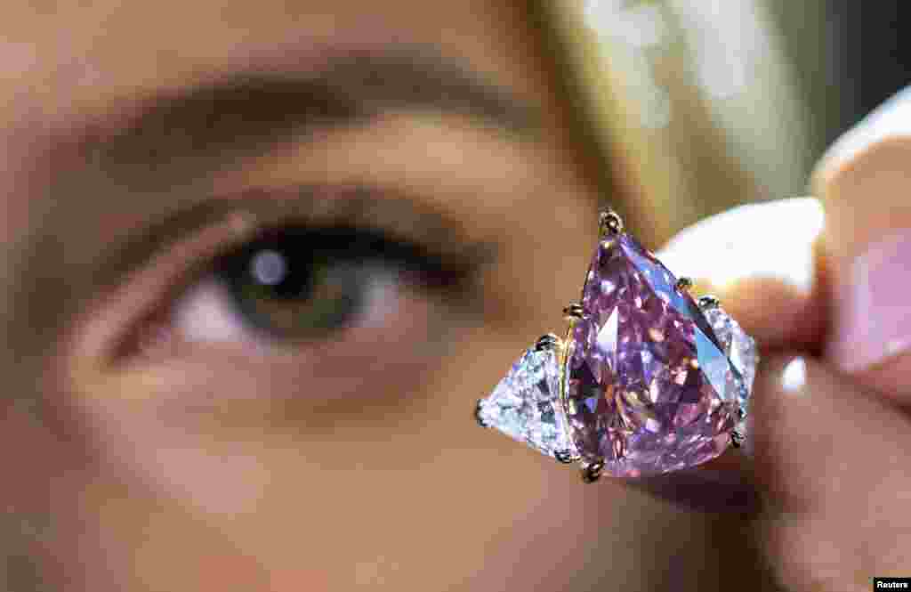 A model holds an 18.18 carat pink diamond called "Fortune Pink" that could fetch 30 million U.S. dollars during a preview at Christie's before the auction sale in Geneva, Switzerland, Nov. 2, 2022.