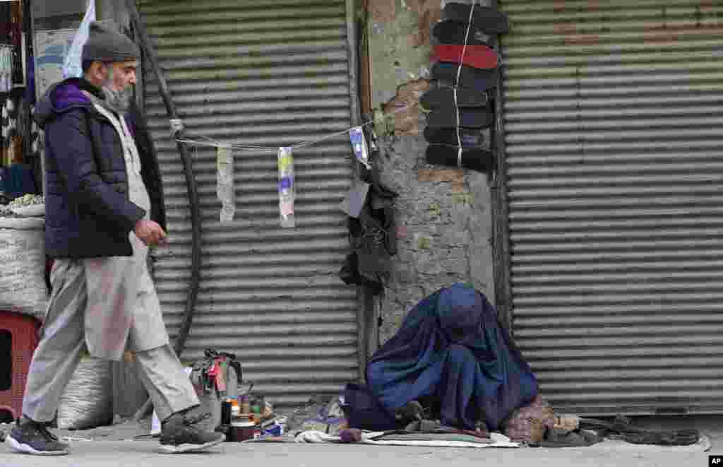 An Afghan refugee cobbler woman, right, repairs a shoe in Peshawar, Pakistan.