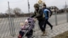 A service member of the Ukrainian armed forces helps to evacuate a child from the town of Irpin, on the only escape route used by locals after days of heavy shelling, while Russian troops advance towards the capital, in Irpin, near Kyiv, Ukraine, March 7, 2022.