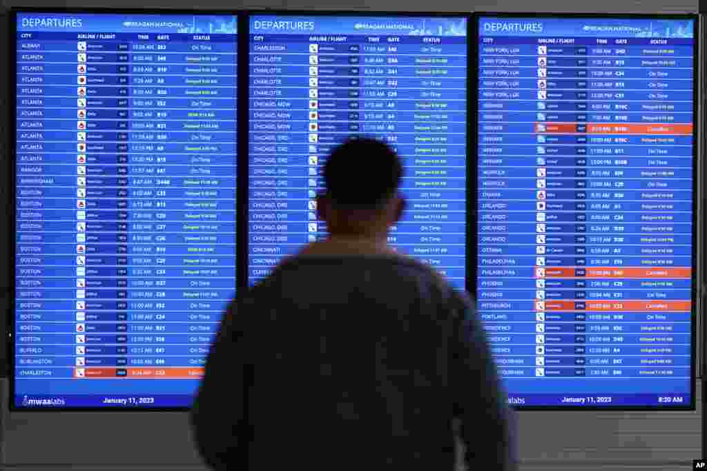 A traveler looks at a flight board with delays and cancellations at Ronald Reagan Washington National Airport in Arlington, Virginia. Flights are being delayed at multiple locations across the United States after a computer outage at the Federal Aviation Administration.