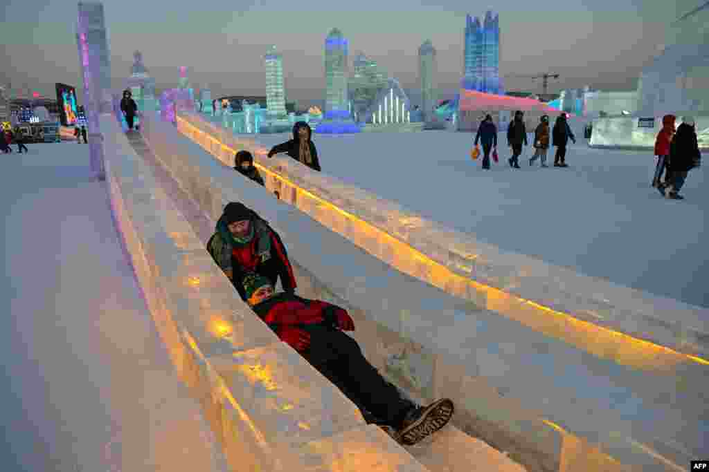 People slide down in an ice slide at the Harbin Ice and Snow World in Harbin, in China's northeastern Heilongjiang province, during the opening ceremony of the 39th Harbin China International Ice and Snow Festival.