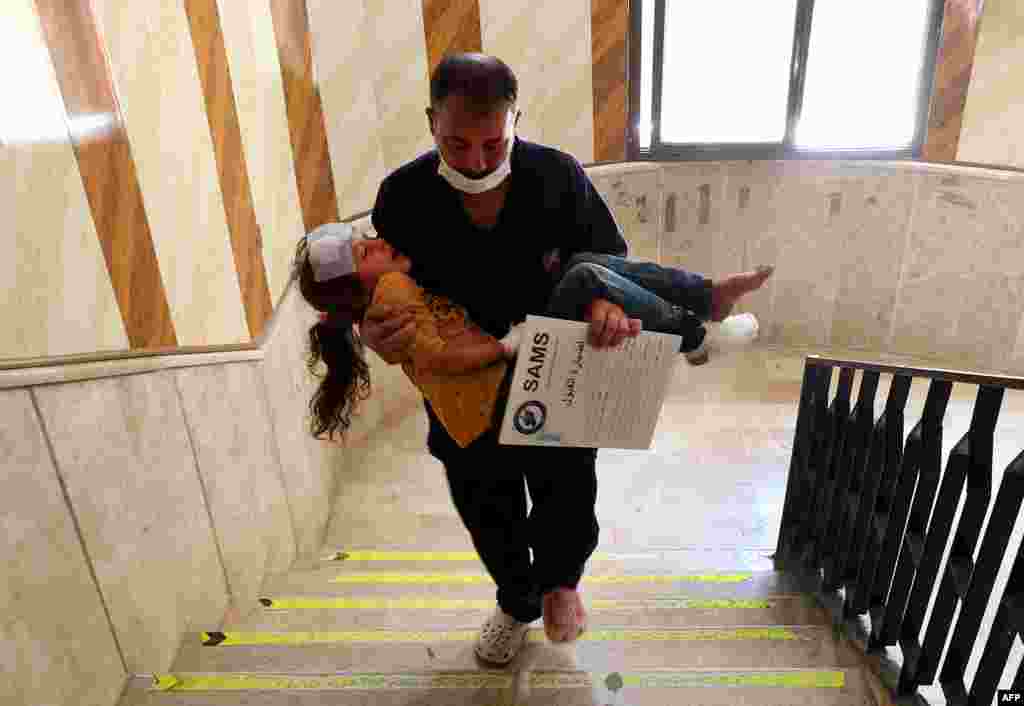 A man carries a girl that was injured during aerial bombardment at a make-shift camp for displaced Syrians, in a hospital in the Atby town of Maaret Misrin in the north of Syria&#39;s rebel-held Idlib province.