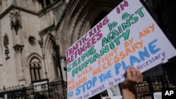 Protesters stand outside the High Court where the ruling on Rwanda deportation flights is taking place, in London on June 13, 2022.