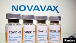 Ilustrasi - Botol dengan stiker bertuliskan, "Hanya vaksin / Injeksi COVID-19 / Coronavirus" dan jarum suntik di depan logo Novavax, 31 Oktober 2020.