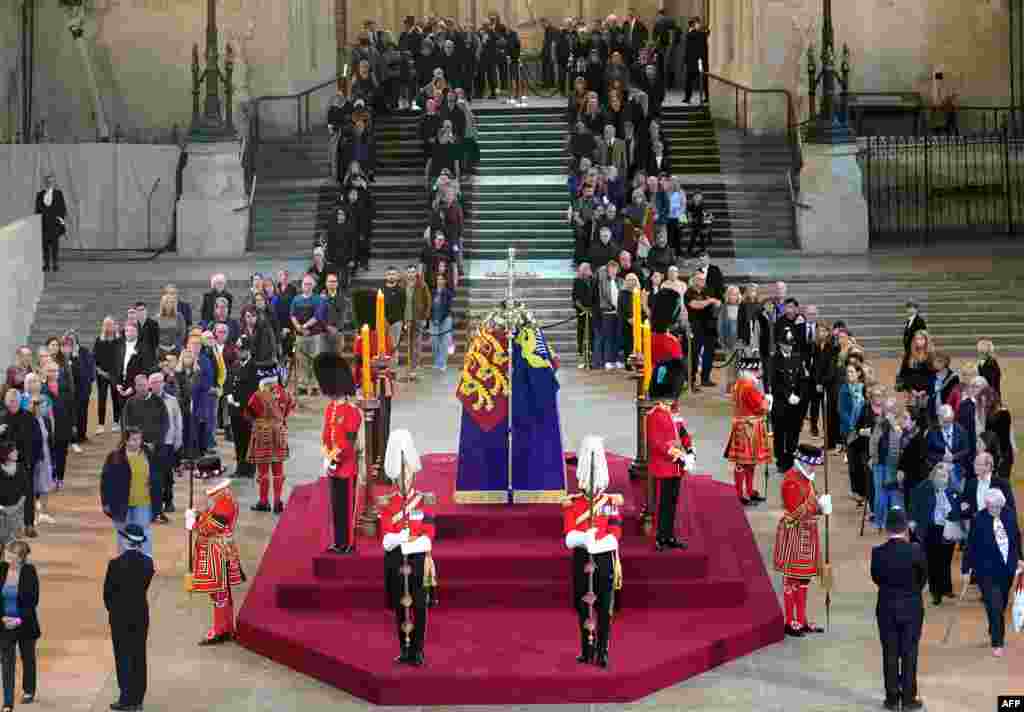 Members of the public file past the coffin of Queen Elizabeth II, draped in the Royal Standard with the Imperial State Crown and the Sovereign&#39;s orb and sceptre, lying in state on the catafalque in Westminster Hall, at the Palace of Westminster, London, ahead of her funeral on Monday.