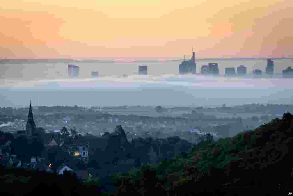 Fog surrounds buildings of the banking districts in Frankfurt, Germany. In foreground the city of Kronberg.