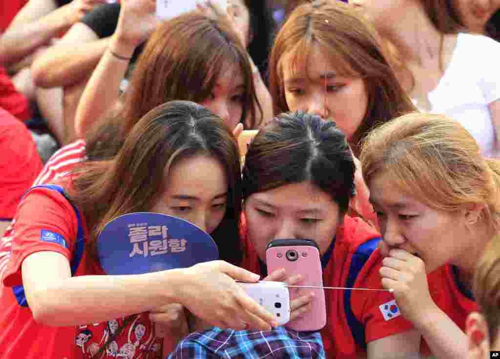 Gadis-gadis Korea Selatan melihat tim Korsel bertanding melawan Rusia dari ponsel pintar mereka karena &#39;layar lebar&#39; untuk nonton bersama (nobar) mati akibat kerusakan teknis di Seoul.