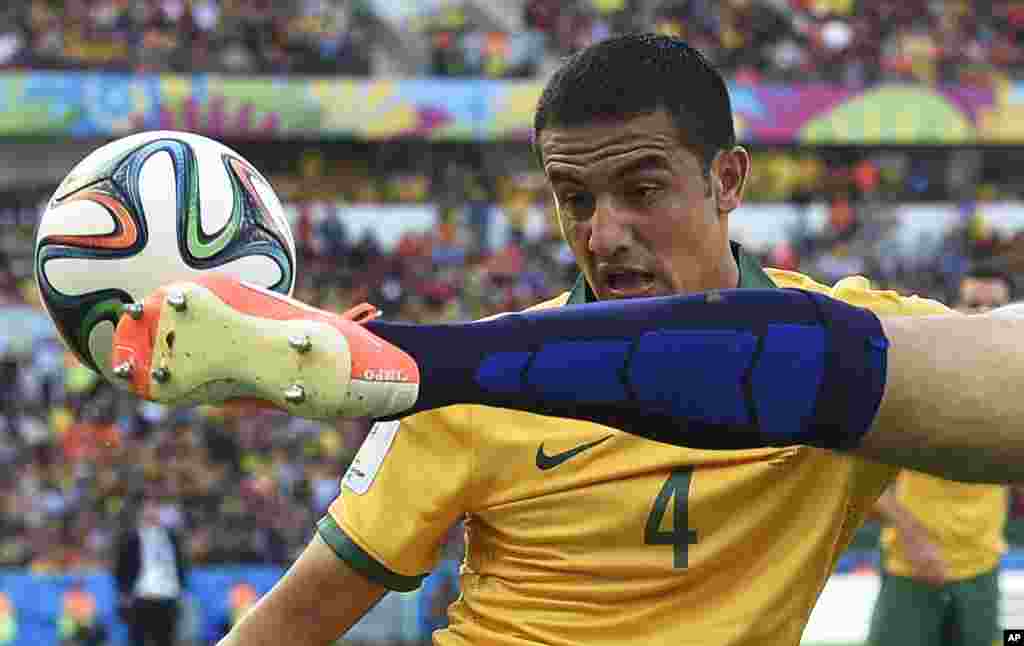 Pemain Australia Tim Cahill (kiri) melihat pemain Belanda Ron Vlaar menghalau bola dalam pertandingan Piala Dunia grup B di Porto Alegre, Brazil.