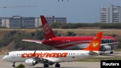 FILE - Airplanes wait their turn to take off on a runway of the Simon Bolivar airport in La Guaira, outside Caracas. 
