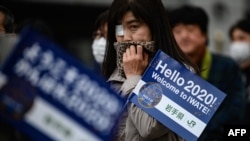 People queue to see the Tokyo 2020 Olympic flame on display outside the railway station in Tono, Iwate prefecture on March 22, 2020. - The flame arrived in Japan to a scaled-down welcoming ceremony on March 20 as doubts grew over whether the 2020…