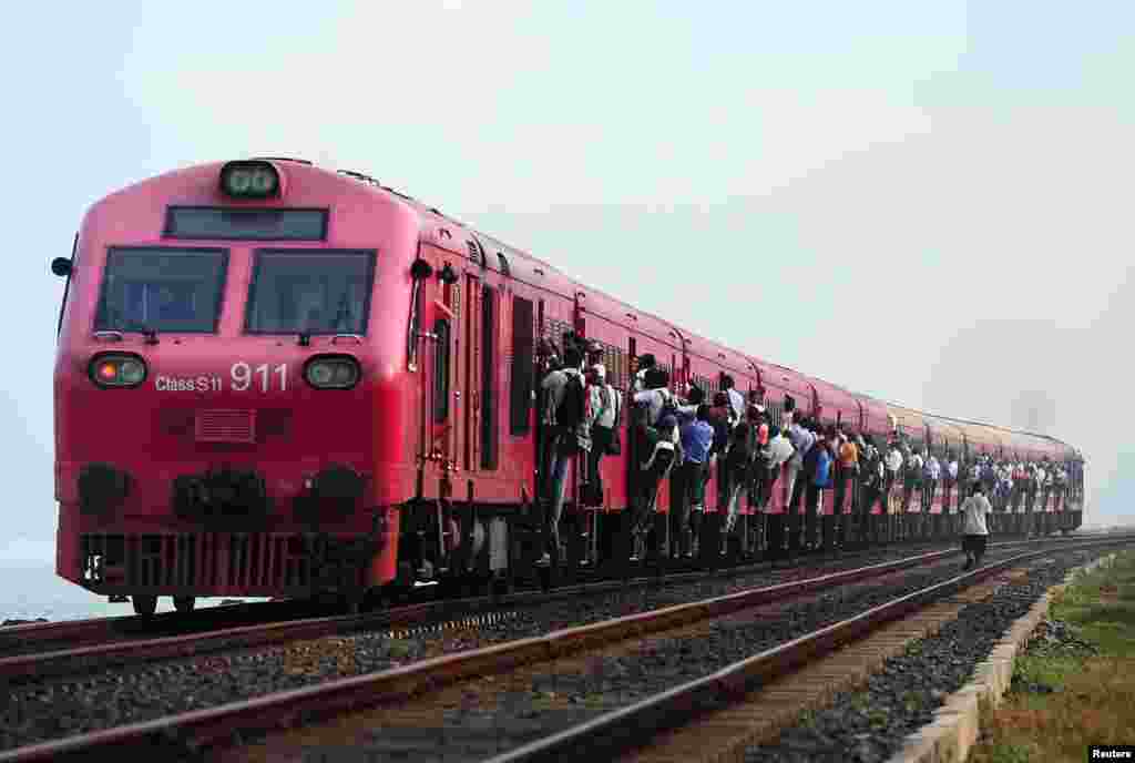 Warga Sri Lanka bergantungan di gerbong kereta penumpang di ibukota Kolombo.
