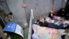 Personas que esperan para solicitar asilo duermen frente a un letrero de la aplicación CBP One mientras acampan cerca de la entrada peatonal del puerto de entrada de San Isidro el 1 de junio de 2023, en Tijuana, México.