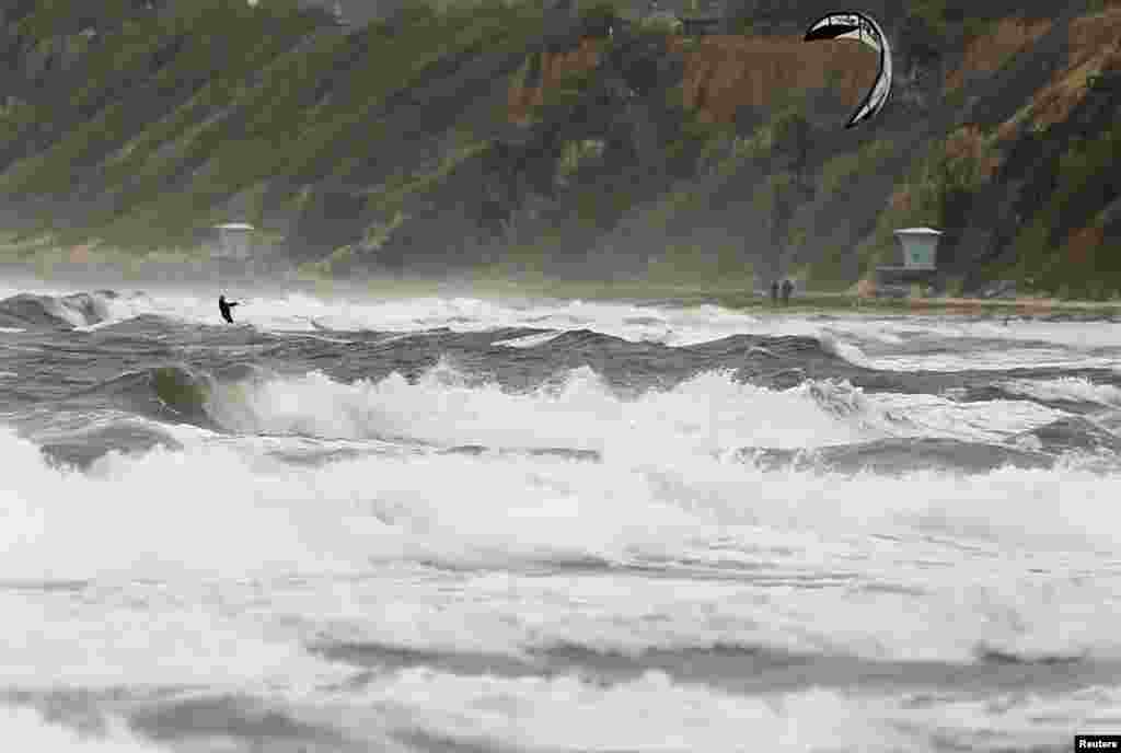 A kite boarder sails through rough seas during an autumn storm off the coast of Cardiff, California, USA, Oct. 9, 2013.