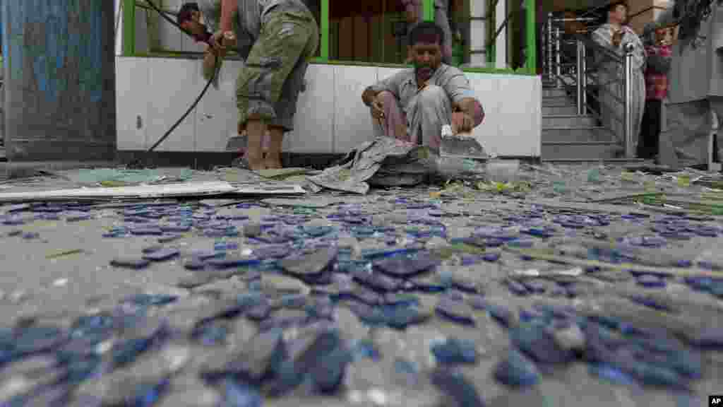 Afghan shopkeepers clean up broken glasses near the site of a suicide attack in Kabul, Afghanistan, Aug. 10, 2014.