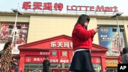 居民在韩国乐天集团在北京开的一家乐天玛特超市前走过。（2017年3月17日）