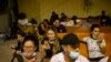 La gente espera y habla con familiares por teléfono en un almacén administrado por el grupo sin fines de lucro Mission: Border Hope, en Eagle Pass, Texas, el 23 de mayo de 2022.