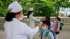 （资料照）2020年6月3日，朝鲜平壤一所小学学生在进入学校前接受体温测量。