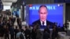 Participants at the St. Petersburg International Economic Forum gather near a screen showing Russian President Vladimir Putin