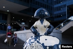 People walk near a sculpture by Venezuelan artist Antonio Azzato as part of the “Meninas Caracas Gallery” street exhibit which plays homage to Spanish artist Diego Velazquez's “Las Meninas” in Caracas, Venezuela January 10, 2024. (REUTERS/Gaby Oraa)