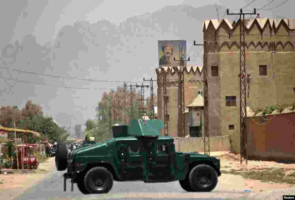 Afghan policemen stand guard near the house belonging to Afghan President Hamid Karzai's cousin, Hashmat Karzai, at the site of a suicide attack in Kandahar, Afghanistan, July 29, 2014.