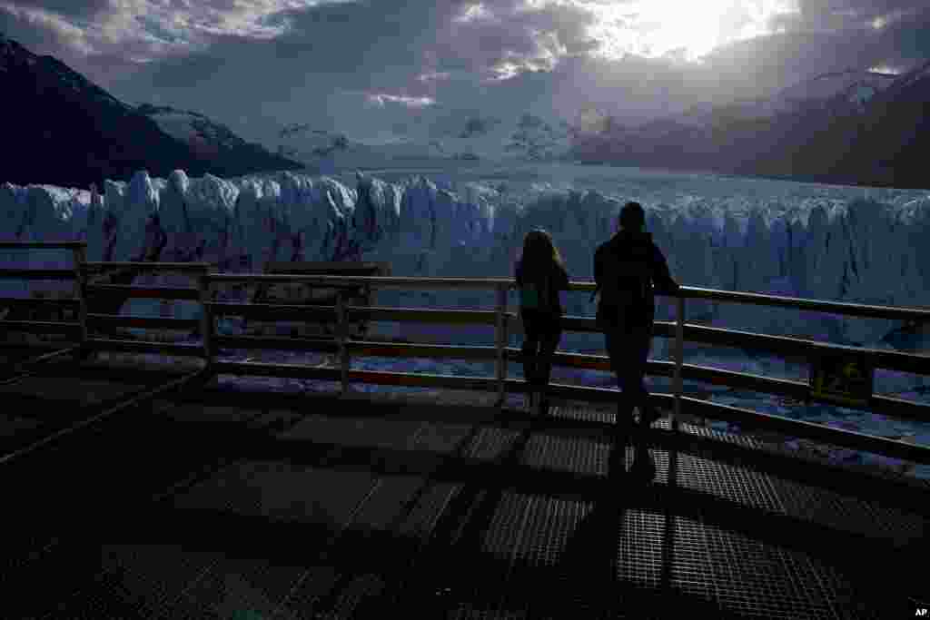 Tourists watch the Perito Moreno Glacier at Los Glaciares National Park, near El Calafate, Argentina, Nov. 1, 2021.