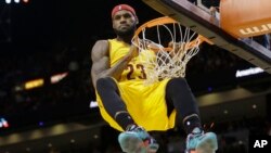Cleveland Cavaliers forward LeBron James (23) hangs onto the basket after a dunk during the second half of an NBA basketball game against the Miami Heat in Miami, Dec. 25, 2014. James was called for a technical foul on the play.