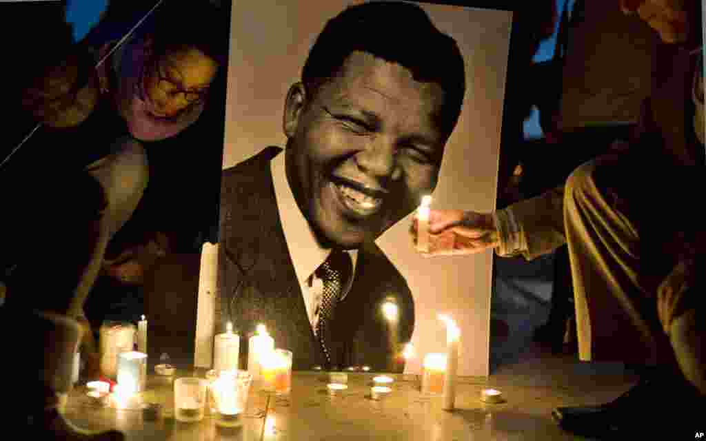 Warga menyalakan lilin di depan foto mantan presiden Afrika Selatan dan pejuang anti-apartheid Nelson Mandela, di alun-alun Trocadero, Paris (15/12). (AP/Thibault Camus)