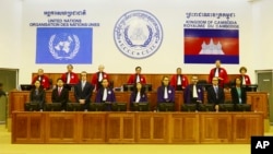In this photo released by the Extraordinary Chambers in the Courts of Cambodia, Judges and clerks of the U.N.-backed war crimes tribunal are standing inside the court hall of the U.N.-backed war crimes tribunal in Phnom Penh, Cambodia, Thursday, Aug. 7, 2