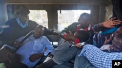 FILE - Protesters are beaten with wooden clubs inside the back of a police pickup truck after being arrested outside the Parliament building in Nairobi, Kenya, in December 2014.