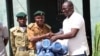 Pastor Yohanna Buru, founder of the Peace, Revival and Reconciliation Foundation, hands the organization's donation to a prison officer at Kaduna Central Prison.