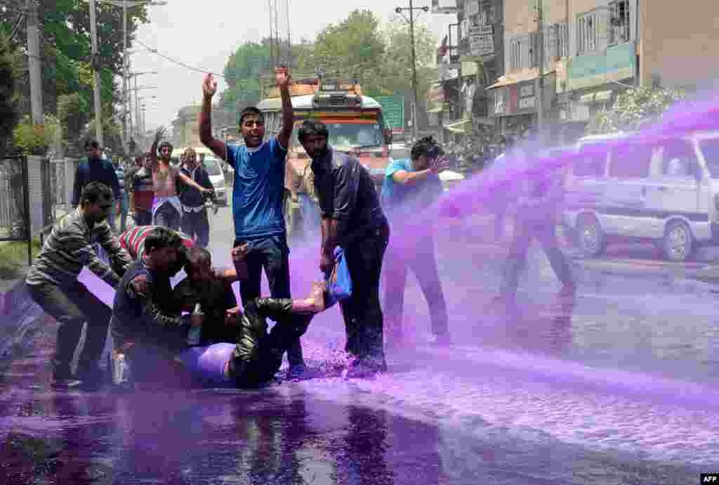 Kashmiri government employees demonstrate as riot police spray purple-dyed water during a protest march in Srinagar. Indian police detained dozens of government employees as they tried to stage a protest march demanding the regularisation of contractual jobs and an increase in salary.