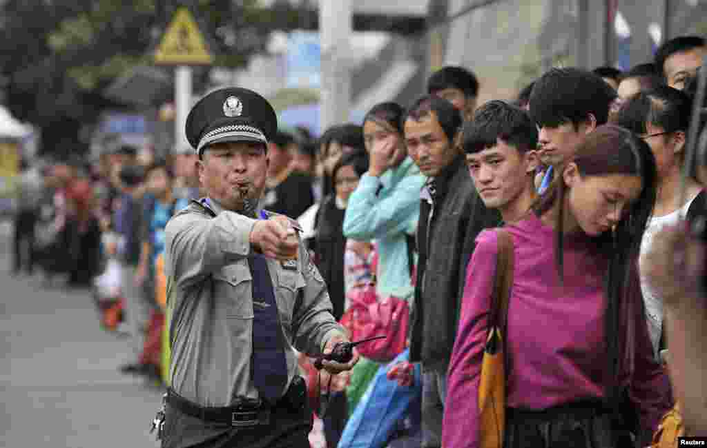 Petugas keamanan di kota Hefei, provinsi Anhui, China berusaha merapikan para calon penumpang di sebuah halte bus, pada puncak lalu lintas selama hari libur nasional di China.