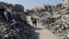 Orang-orang Palestina berjalan melewati bangunan yang hancur akibat serangan Israel di kamp pengungsi Jabaliya di Jalur Gaza, Kamis, 29 Februari 2024. (Foto: AP Photo/Mahmoud Essa)