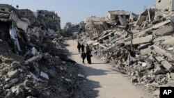 Orang-orang Palestina berjalan melewati bangunan yang hancur akibat serangan Israel di kamp pengungsi Jabaliya di Jalur Gaza, Kamis, 29 Februari 2024. (Foto: AP Photo/Mahmoud Essa)