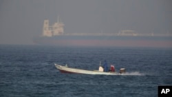 Ribarski brzi čamac prolazi ispred tankera koji se nazire u daljini, Fuđairi, Ujedinjeni Arapski Emirati, 15. juna 2019.