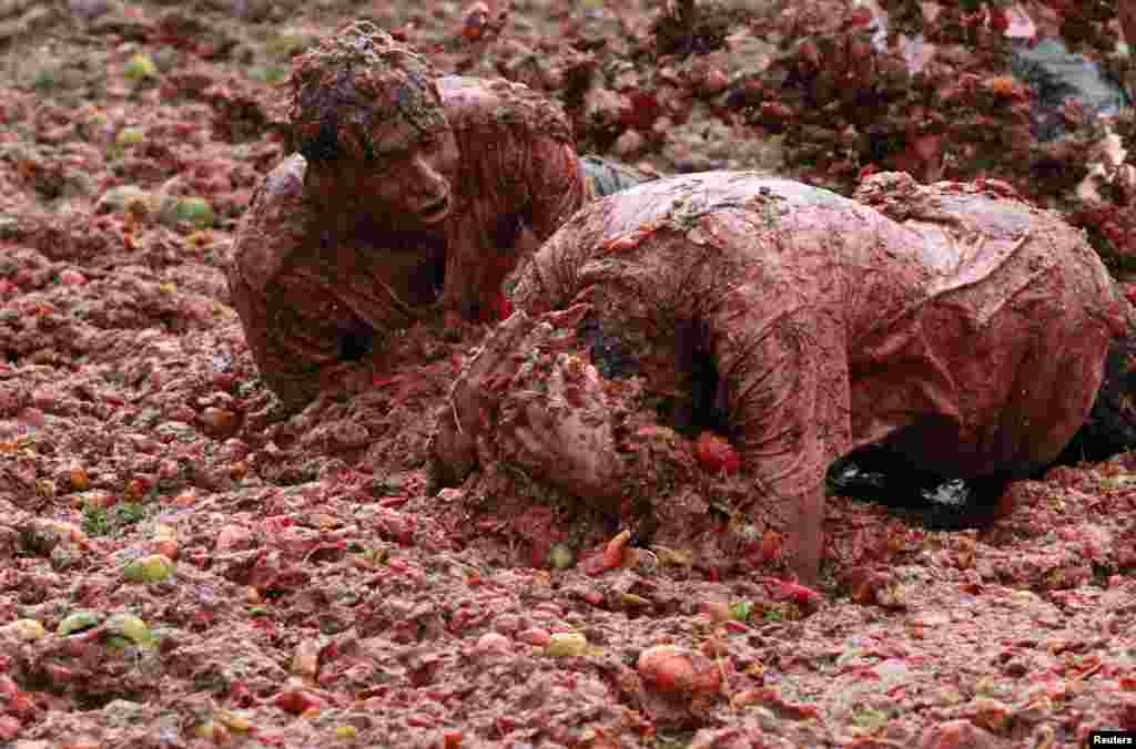 Warga bersuka ria bermain dengan bubur tomat selama acara tradisional tahunan "Tomatina" (perang tomat), di Boyaca, provinsi Sutamarchan, Kolombia.