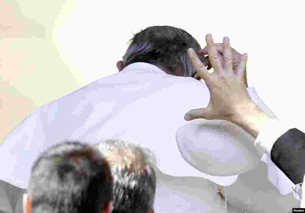 Seorang anggota keamanan mencoba menangkap 'kopiah' Paus Fransiskus yang tertiup angin pada akhir khutbah mingguan di Lapangan Santo Petrus, Vatikan.