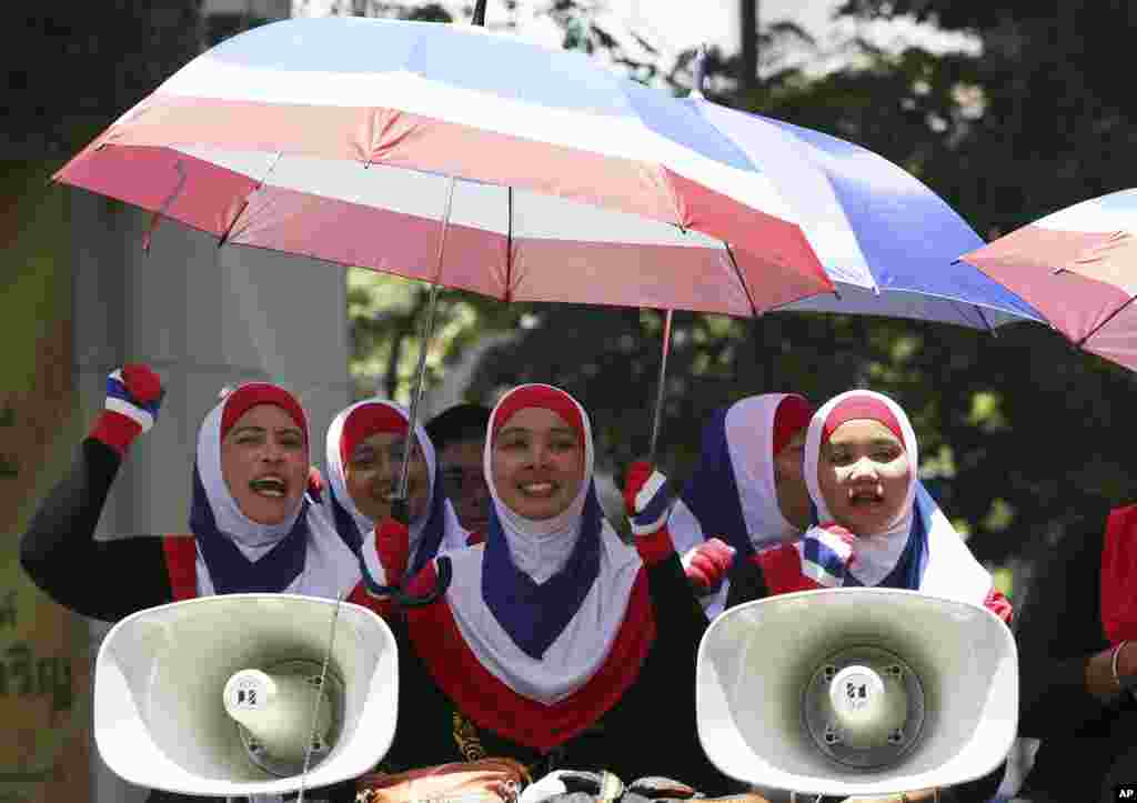 Para demonstran anti-pemerintah bernyanyi saat menumpang truk, merayakan keputusan Mahkamah Konstitusi yang meminta Perdana Menteri Yingluck Shinawatra untuk mundur, sebuah kemenangan bagi upaya para demonstran selama enam bulan terakhir di Bangkok (8/5). (AP/Apichart Weerawong)
