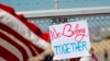 A protester holds a sign outside a closed gate at the Port of Entry facility, June 21, 2018, in Fabens, Texas, where tent shelters are being used to house separated family members.