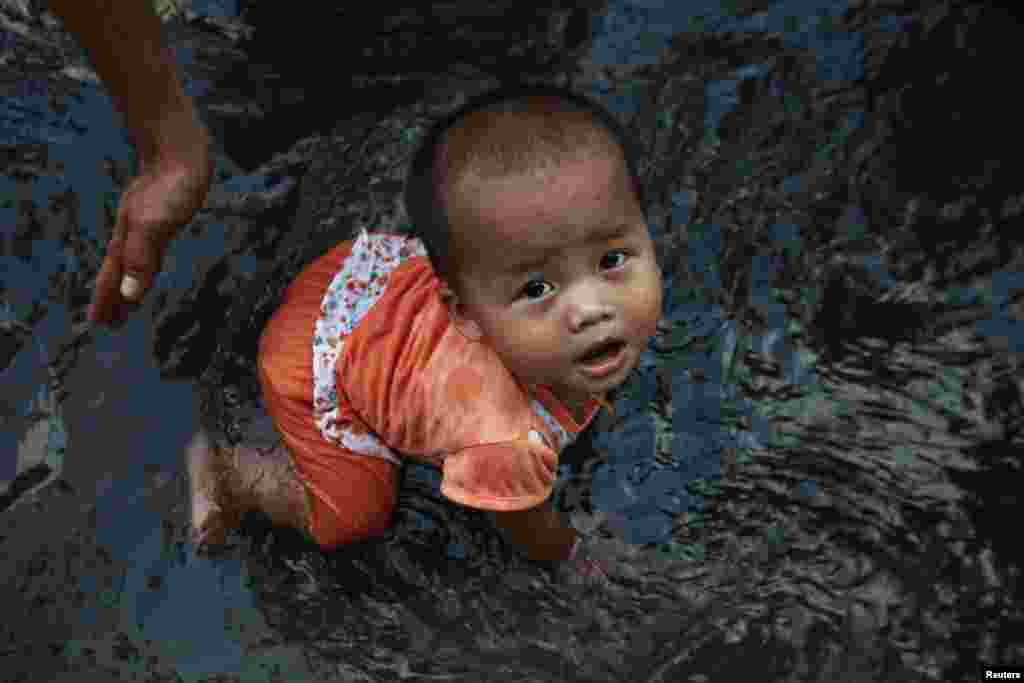 Seorang bayi perempuan bermain air pada perayaan Tahun Baru di Rangoon, Burma.